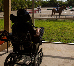 person in wheelchair looking at horse and rider